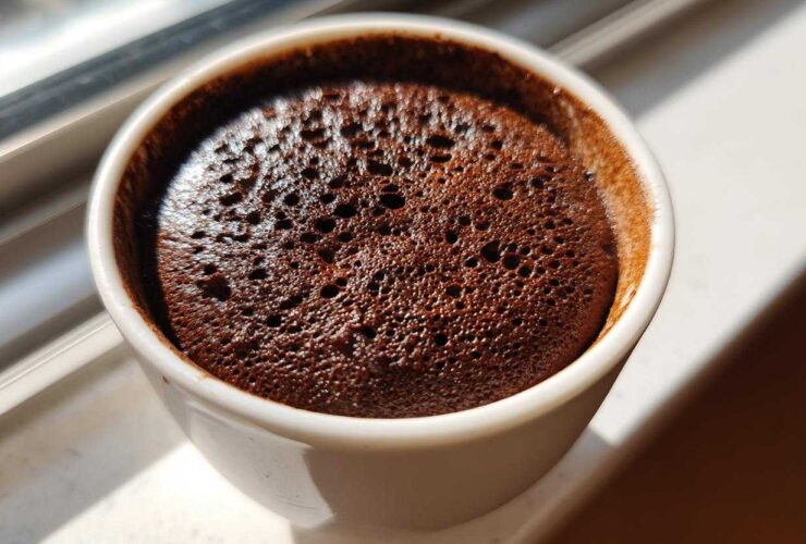 Close-up view of the airy, bubbly texture of homemade chocolate mousse in a small white cup.