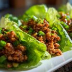 Close-up of several chicken lettuce wraps filled with savory ground chicken and topped with green onions.