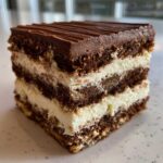 A perfect square slice of brownie refrigerator cake showing alternating dark chocolate layers and thick white cream filling.