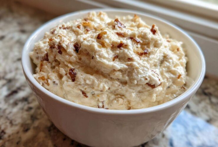 A close-up of creamy, homemade onion dip topped with caramelized onions served in a white bowl.