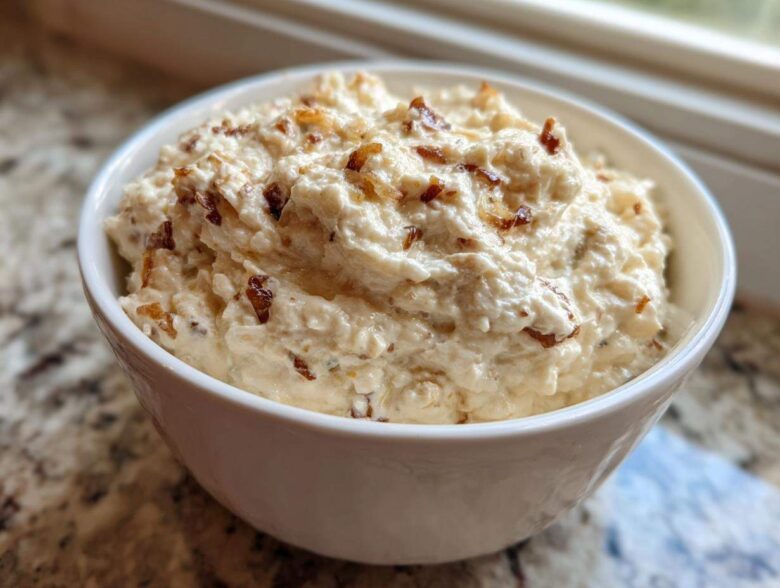 A close-up of creamy, homemade onion dip topped with caramelized onions served in a white bowl.