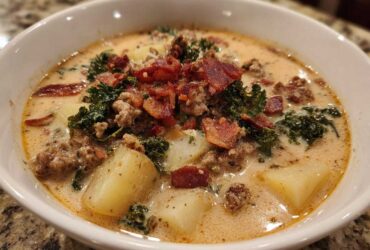 Close-up of a creamy bowl of Zuppa Toscana soup topped with sausage, bacon, and kale.