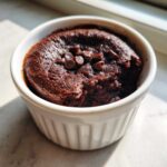 A rich, dark Cottage Cheese Microwave Brownie topped with chocolate chips in a white ramekin.