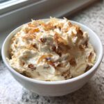 Close-up of creamy, homemade onion dip topped with caramelized onions in a white serving bowl.