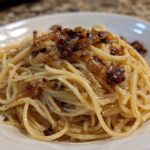 Close-up of creamy caramelized onion pasta tossed with spaghetti noodles and topped with rich, dark caramelized onions.