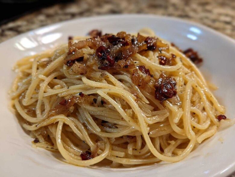 Close-up of creamy caramelized onion pasta tossed with spaghetti noodles and topped with rich, dark caramelized onions.