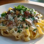 A serving of fettuccine pasta coated in creamy sauce with pieces of chicken and topped with fresh parsley, representing chicken alfredo.
