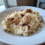 Close-up of creamy chicken and rice topped with melted cheese and browned chicken pieces.