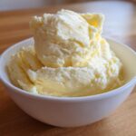 A close-up of a white bowl overflowing with incredibly creamy and fluffy mashed potatoes.