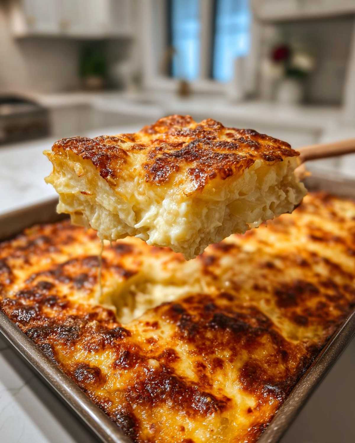 A generous slice of creamy scalloped potatoes with a deeply browned, cheesy top being lifted from the baking dish.