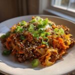 A close-up of a delicious serving of egg roll in a bowl topped with green onions and sesame seeds.