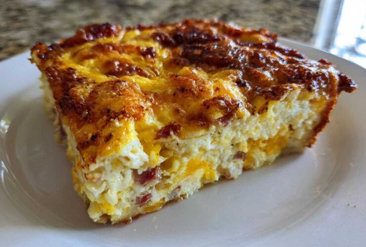 A close-up of a hearty slice of breakfast egg bake with a deeply browned, cheesy top.