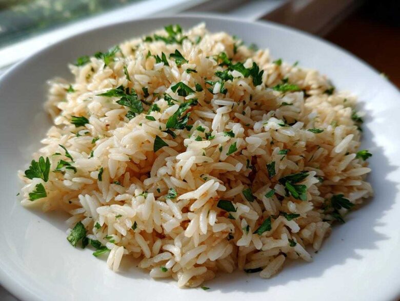 Close-up of fluffy, perfectly cooked rice pilaf garnished generously with chopped fresh parsley on a white plate.