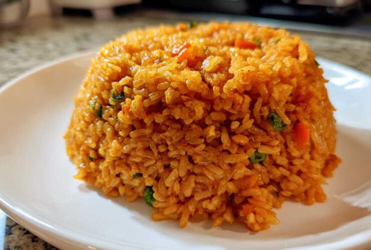 A perfectly molded mound of fluffy, orange-red Spanish rice served on a white plate.