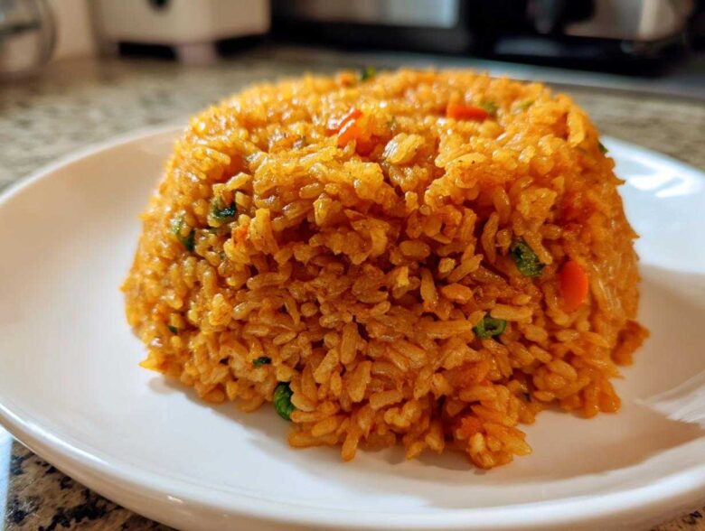 A perfectly molded mound of fluffy, orange-red Spanish rice served on a white plate.