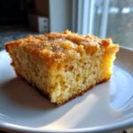 A close-up, golden-brown square slice of baked oatmeal resting on a white plate.