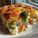 A close-up view of a creamy vegetable casserole slice featuring broccoli and carrots with a golden, crispy breadcrumb topping.