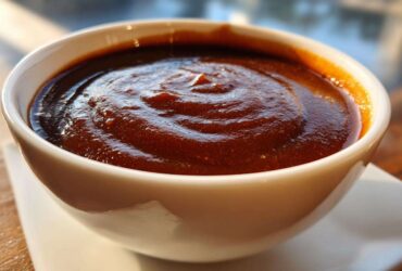 Close-up of thick, rich homemade brown gravy with swirling textures in a small white bowl.