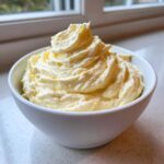 A bowl filled with freshly whipped, creamy garlic aioli, piped high with swirls.