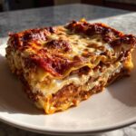 A thick, layered slice of homemade lasagna with rich meat sauce and creamy ricotta, topped with bubbly, browned cheese.