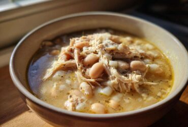A close-up of a bowl filled with rich Instant Pot White Chicken Chili, featuring shredded chicken and white beans in a creamy broth.