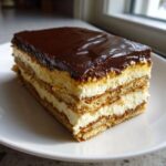 A rich, layered slice of no-bake chocolate eclair cake with graham crackers, cream filling, and chocolate glaze.