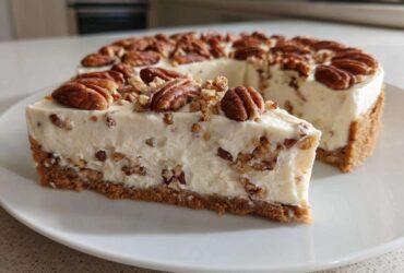 A slice of creamy, no-bake pecan cream pie sits on a white plate, topped with whole pecans.