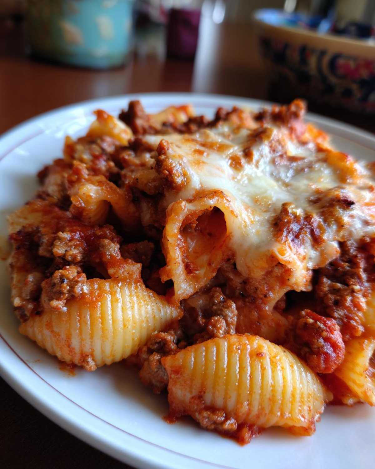 Close-up of a serving of cheesy enchilada pasta with ground meat sauce and shell pasta.