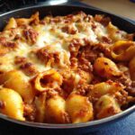 Close-up of one pot enchilada pasta made with shell pasta, meat sauce, and bubbly melted cheese.