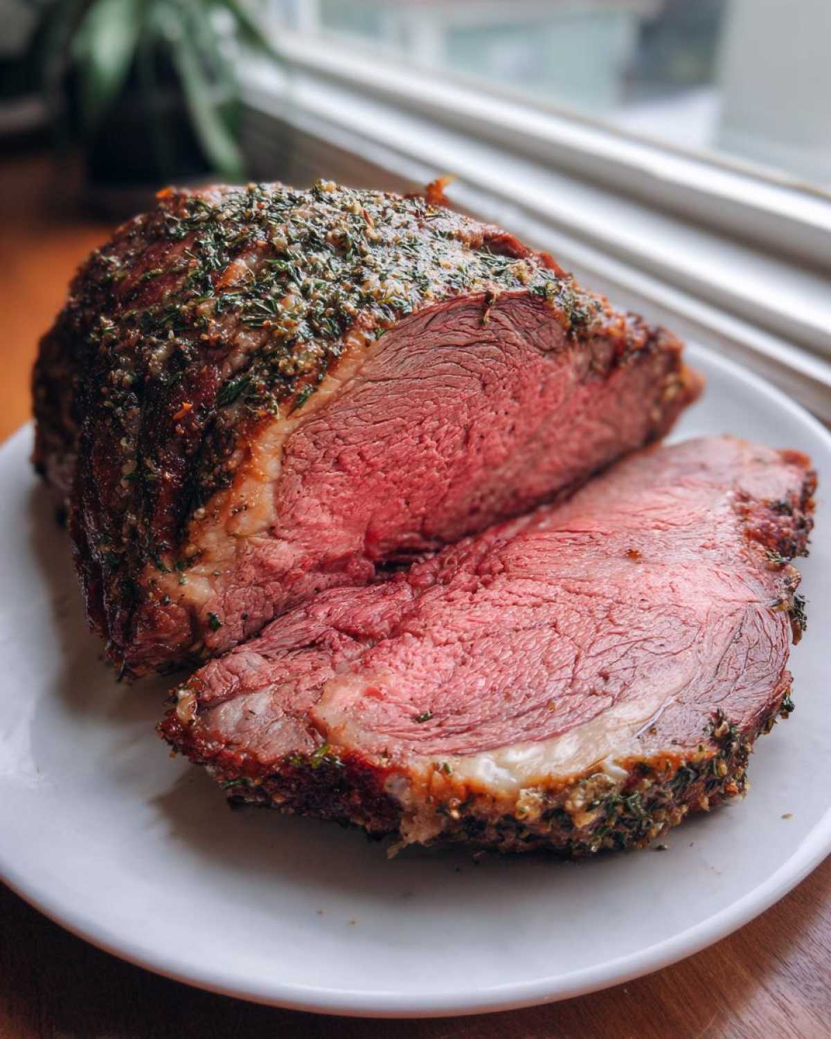 Close-up of a perfectly cooked prime rib roast oven, sliced to show medium-rare pink center and herb crust.