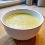 Close-up of a bowl of smooth, pale green celery soup showing its velvety texture.