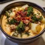 Close-up of a hearty bowl of Zuppa Toscana soup topped with crumbled bacon, kale, and potatoes.