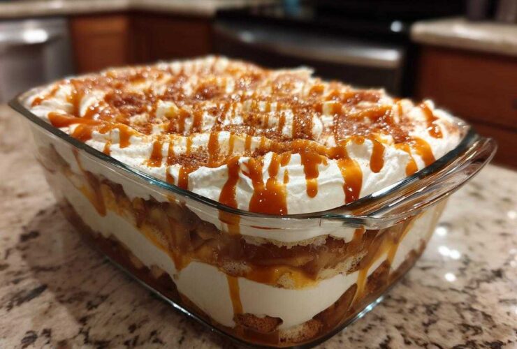 Close-up of a delicious caramel apple trifle layered in a glass dish, topped with whipped cream and caramel drizzle.