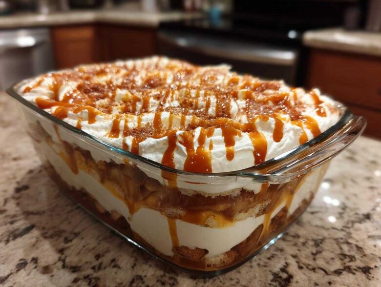 Close-up of a delicious caramel apple trifle layered in a glass dish, topped with whipped cream and caramel drizzle.