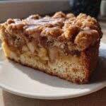 Close-up of a moist slice of apple crumb cake topped with a caramel glaze.