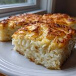 Close-up of two squares of cheesy potato casserole with a golden brown, baked cheese topping.