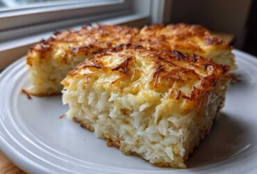 Close-up of two squares of cheesy potato casserole with a golden brown, baked cheese topping.
