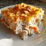 A close-up of a creamy chicken and rice casserole slice topped with golden brown crunchy crumbs.