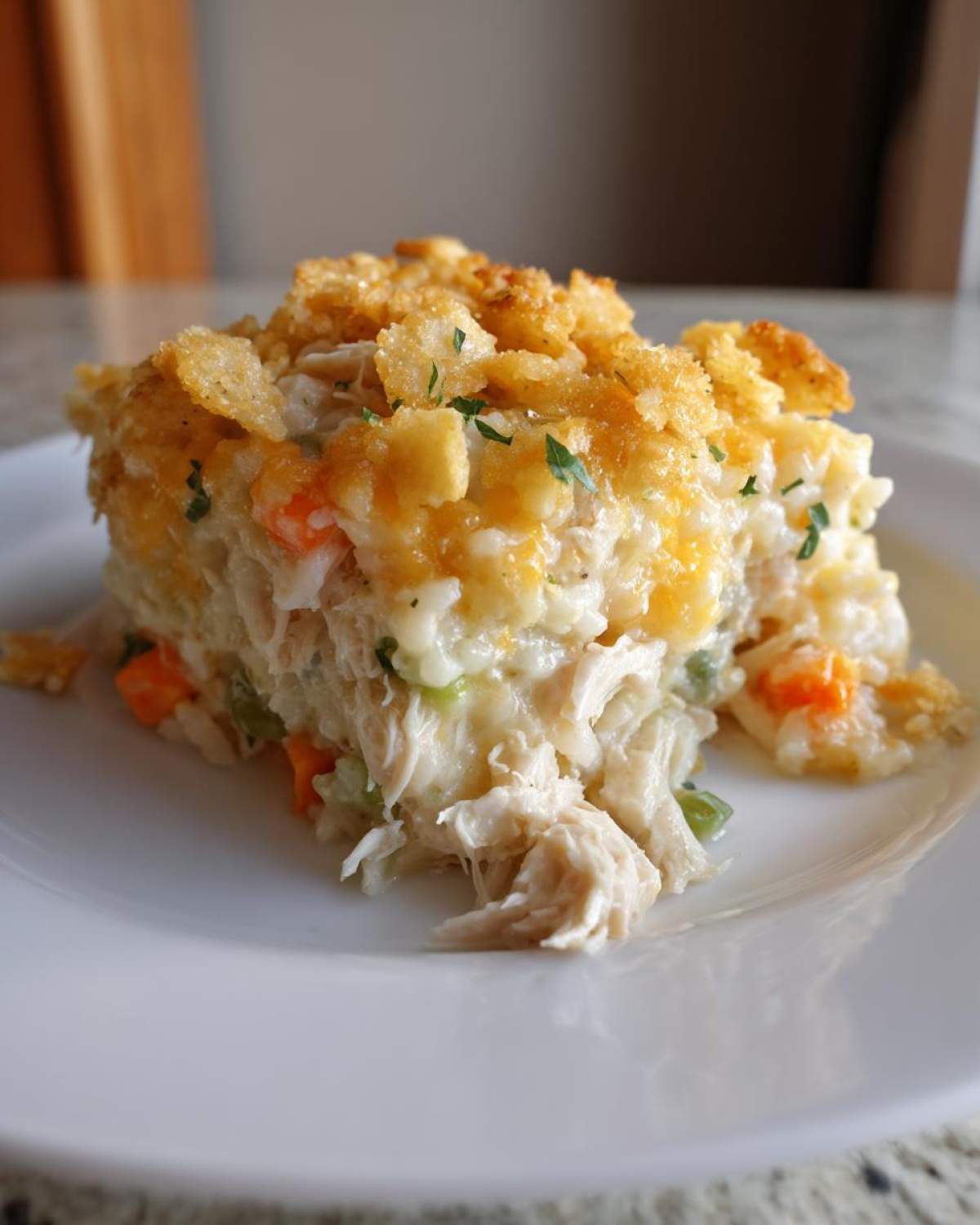 A serving of cheesy chicken and rice casserole featuring shredded chicken, vegetables, and a crunchy golden topping.