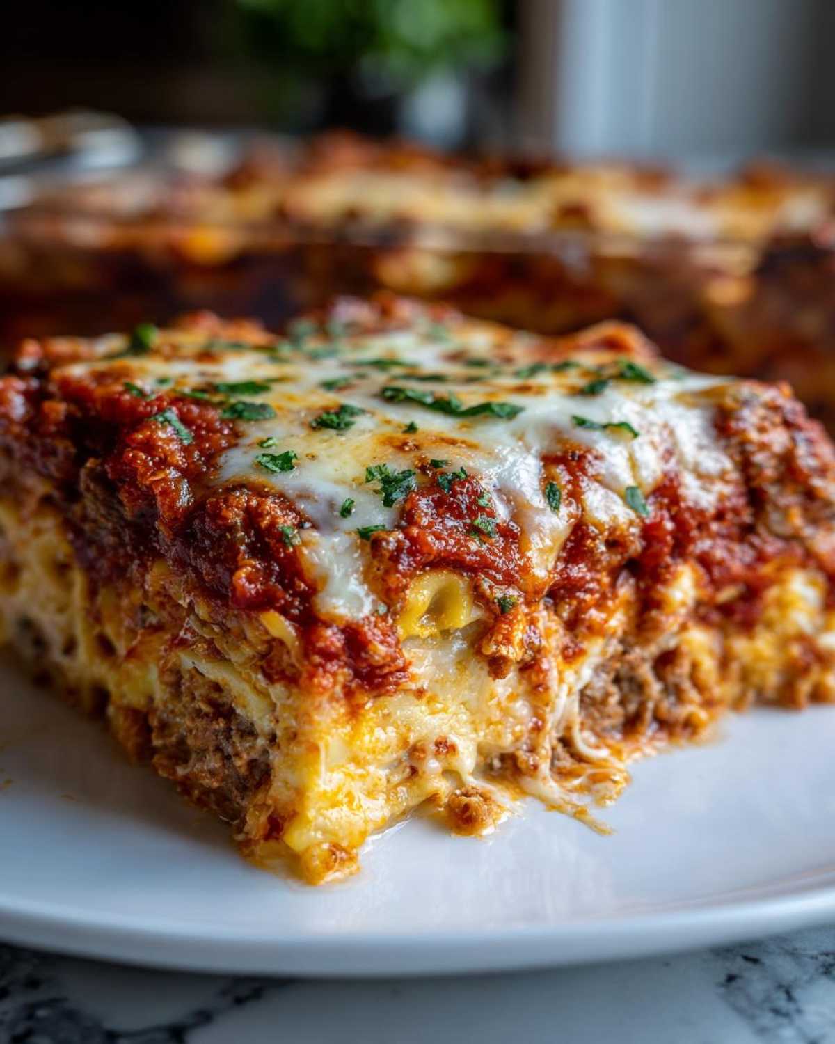Close-up of a rich, cheesy slice of baked ravioli covered in meat sauce and melted mozzarella.