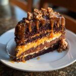 A decadent slice of chocolate caramel toffee crunch cake layered with dark chocolate cake and thick caramel filling.
