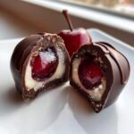 Close-up of a chocolate covered cherries cut in half, showing the gooey cherry center and white fondant layer.
