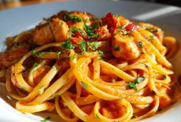 A close-up, appetizing shot of creamy cajun chicken pasta tossed with linguine and topped with fresh parsley.