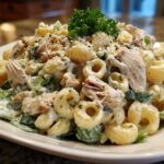 Close-up of creamy chicken caesar pasta salad featuring elbow macaroni, shredded chicken, and romaine lettuce, topped with Parmesan and parsley.