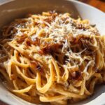 Close-up of creamy french onion pasta coated in sauce, topped with caramelized onions and grated Parmesan cheese.