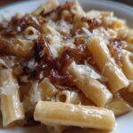 Close-up of creamy french onion pasta topped with caramelized onions and shaved Parmesan cheese.