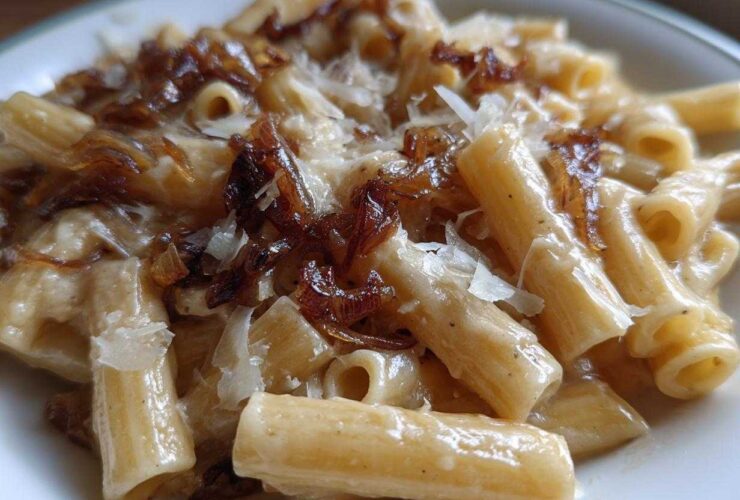 Close-up of creamy french onion pasta topped with caramelized onions and shaved Parmesan cheese.