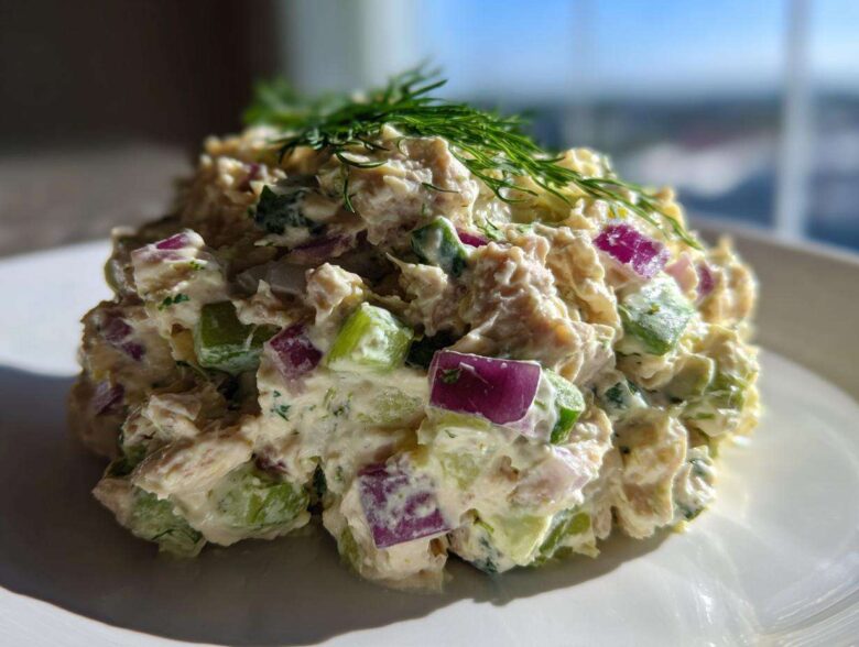 A generous scoop of healthy tuna salad mixed with diced red onion and celery, topped with fresh dill.