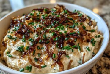Close-up of a creamy homemade onion dip topped generously with crispy caramelized onions and fresh chopped chives.
