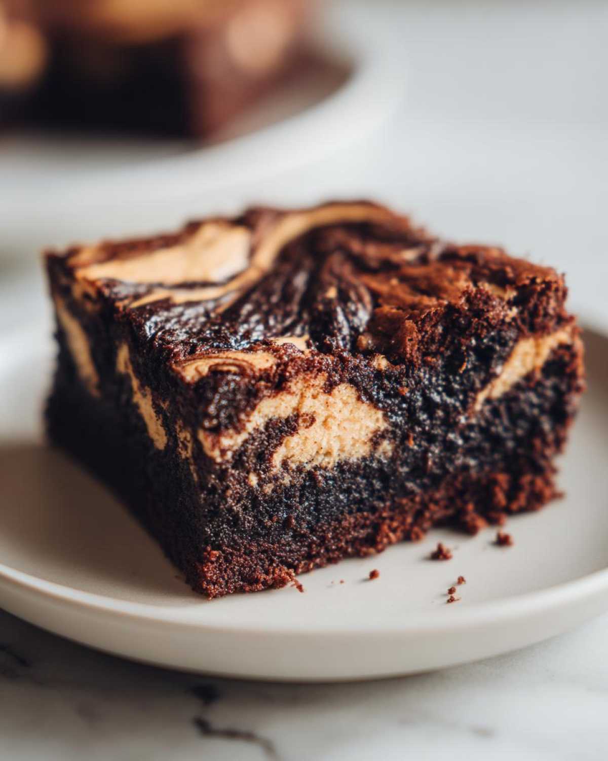 A close-up of a fudgy peanut butter swirl brownies square served on a light plate.